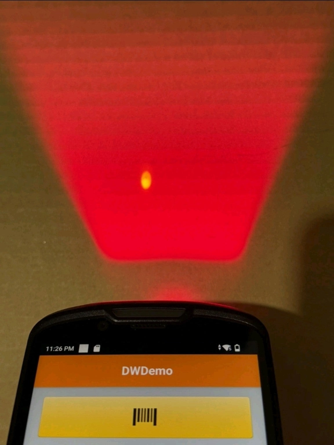 Actual barcode scanning demonstration photographed on Zebra handheld, DWDemo screen and red scanner illumination